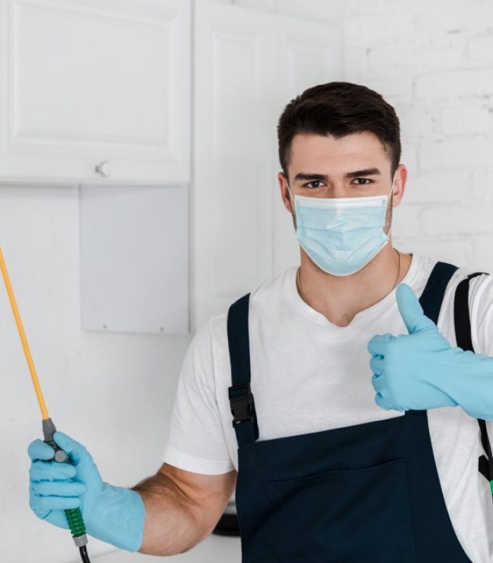 exterminator-in-uniform-holding-toxic-spray-and-showing-thumb-up.jpg